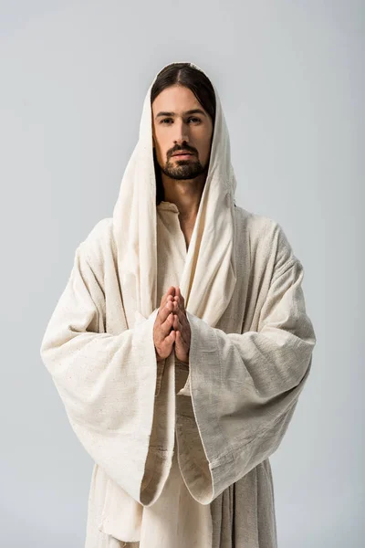 Релігійний чоловік з молитовними руками та халатом Ісуса з капюшоном, що стоїть ізольовано на сірому — стокове фото