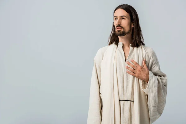 Hombre religioso con la mano en el pecho aislado en gris - foto de stock