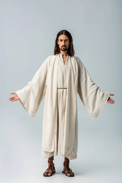 Релігійний чоловік в халаті Ісуса, що стоїть з витягнутими руками на сірому — стокове фото