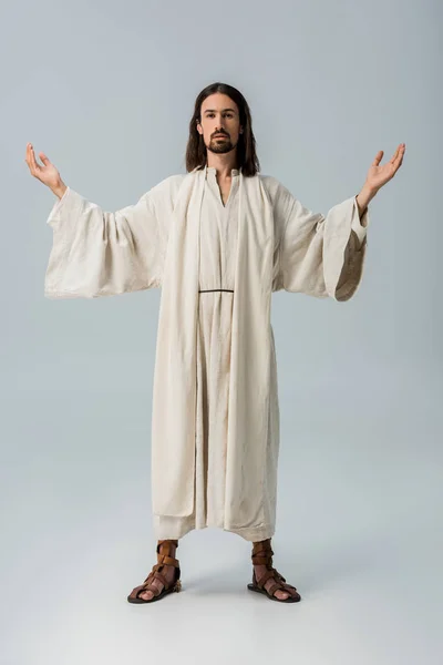 Bärtiger Mann im Jesusgewand mit ausgestreckten Händen auf grau — Stockfoto