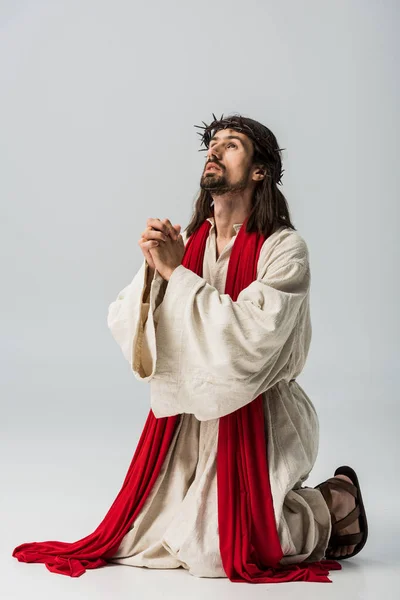 Jésus en couronne priant à genoux sur le gris — Photo de stock