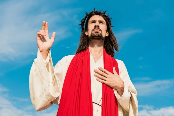 Low angle view of jesus praying with hand on chest — Stock Photo