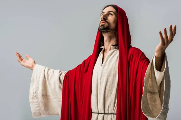 Bearded man in red hood praying with outstretched hands isolated on grey — Stock Photo