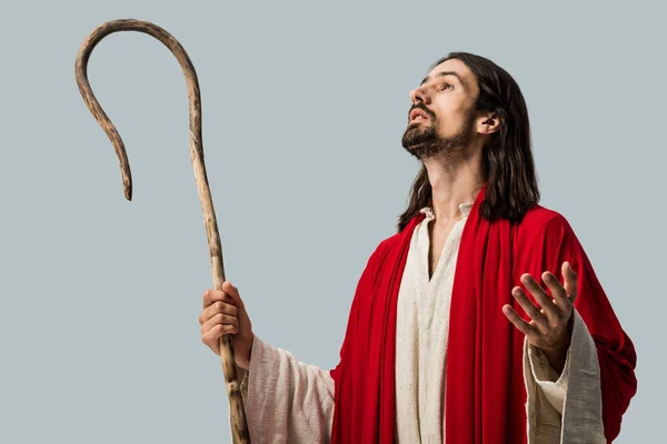 Bearded man in jesus robe holding wooden cane and gesturing isolated on grey — Stock Photo