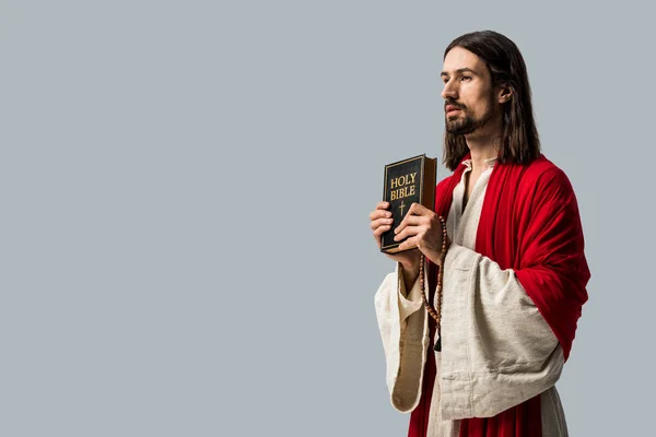 Hombre barbudo guapo sosteniendo la Biblia santa aislado en gris - foto de stock