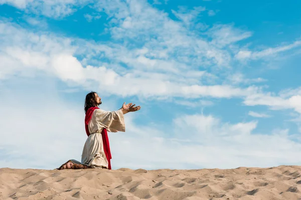 Иисус молится на коленях в пустыне против неба — стоковое фото
