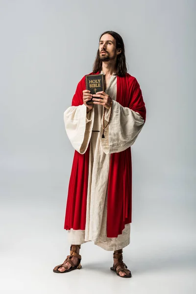 Handsome religious man holding holy bible on grey — Stock Photo