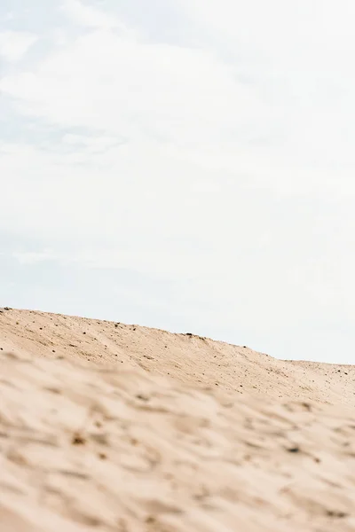 Selective focus of wavy and golden sand against sky with clouds in desert — Stock Photo