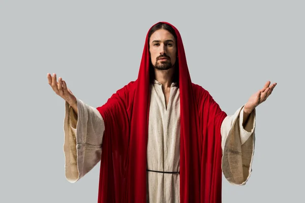 Иисус в красном капюшоне с протянутыми руками, изолированными на сером — стоковое фото