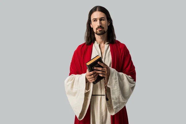 Handsome man looking at camera while holding holy bible isolated on grey — Stock Photo