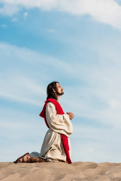 Jesus praying with closed eyes in desert against blue sky — Stock Photo