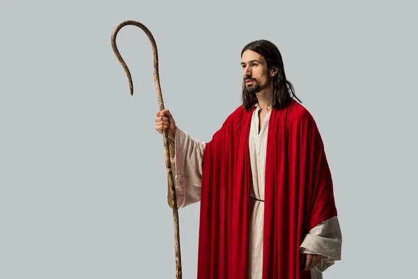 Upset man in jesus robe holding wooden cane isolated on grey — Stock Photo
