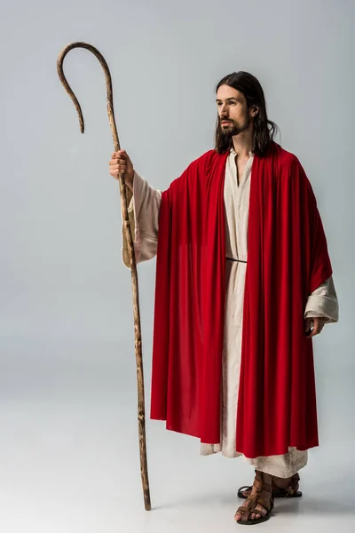 Uomo triste in vestaglia Gesù tenendo canna di legno su grigio — Foto stock