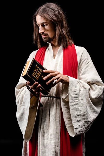 Religieux en Jésus robe tenant sainte bible isolé sur noir — Photo de stock