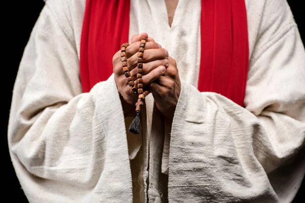 Cropped view of man holding rosary beads isolated on black — Stock Photo