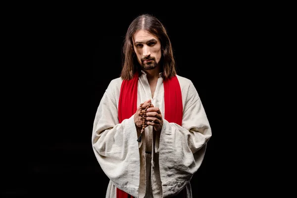 Religioso sosteniendo rosario perlas aisladas en negro - foto de stock