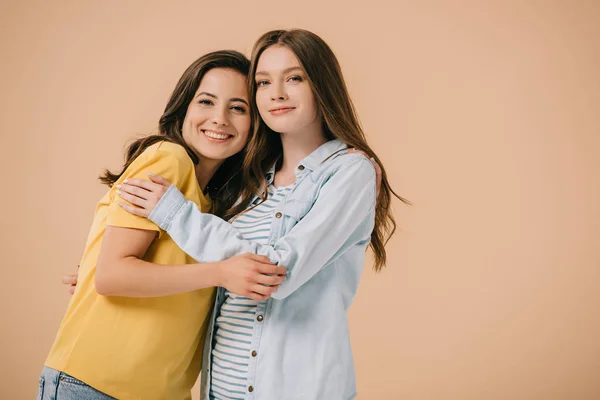 Attractive and smiling friends hugging and looking at camera isolated on beige — Stock Photo
