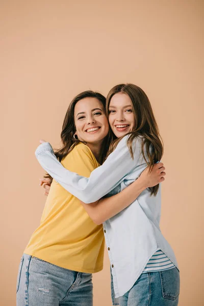Attractive and smiling friends hugging and looking at camera isolated on beige — Stock Photo