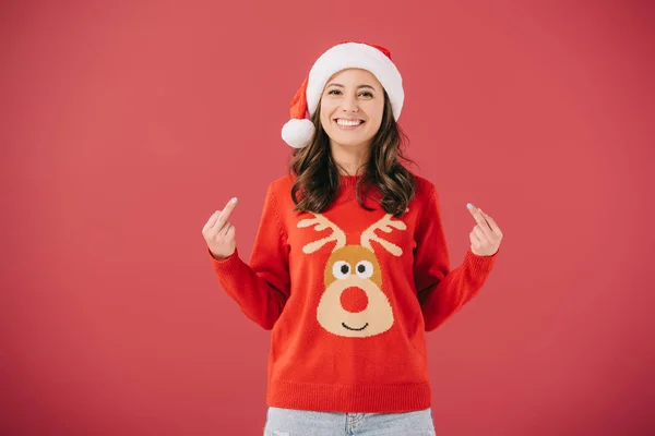 Mulher atraente e sorridente em santa chapéu e suéter mostrando dedos médios isolados em vermelho — Fotografia de Stock