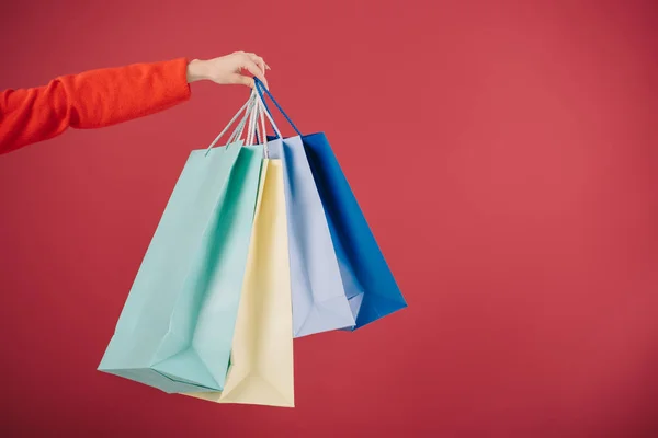 Vista recortada de la mujer sosteniendo bolsas aisladas en rojo - foto de stock