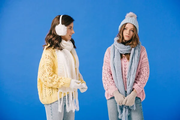 Attractive and sad women in sweaters and scarves looking at camera isolated on blue — Stock Photo