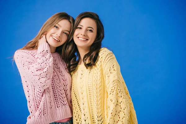 Attractive and smiling women in sweaters looking at camera isolated on blue — Stock Photo