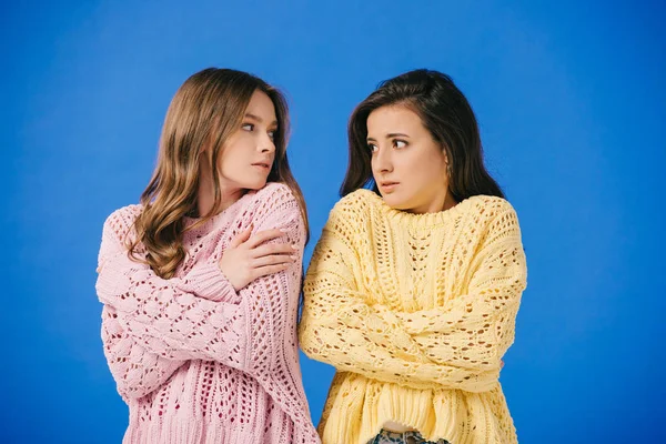Привабливі жінки в светрах дивляться один на одного і відчувають холод ізольовані на синьому — стокове фото