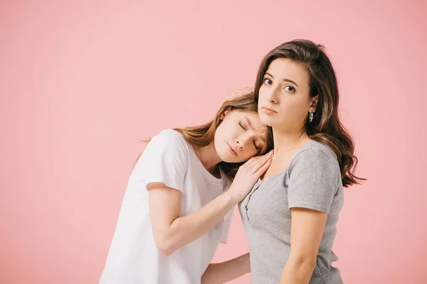 Mulheres atraentes e tristes em camisetas abraçando isolado em rosa — Fotografia de Stock