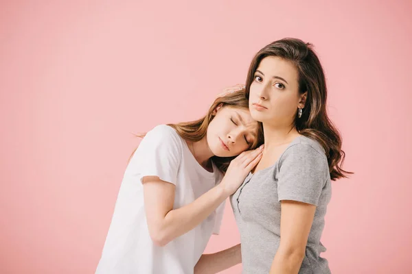 Jolies et tristes femmes en t-shirts câlins isolés sur rose — Photo de stock