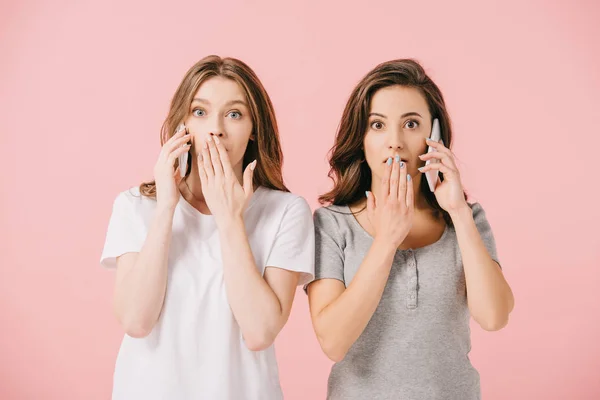 Donne attraenti e scioccate in t-shirt che parlano su smartphone isolati su rosa — Foto stock