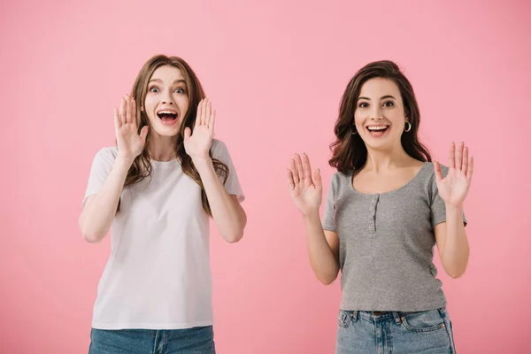 Mujeres atractivas y sonrientes en camisetas mirando a la cámara aislada en rosa - foto de stock