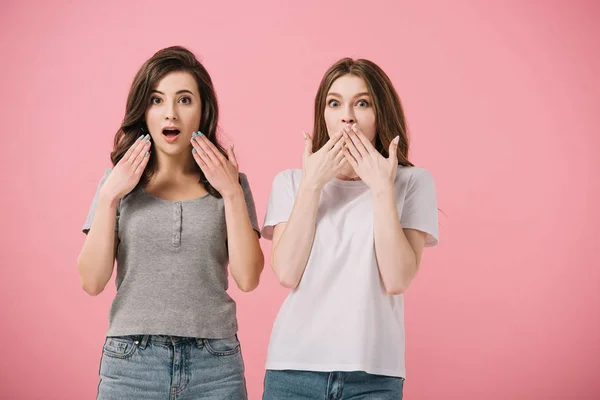 Attractive and shocked women in t-shirts looking at camera isolated on pink — Stock Photo