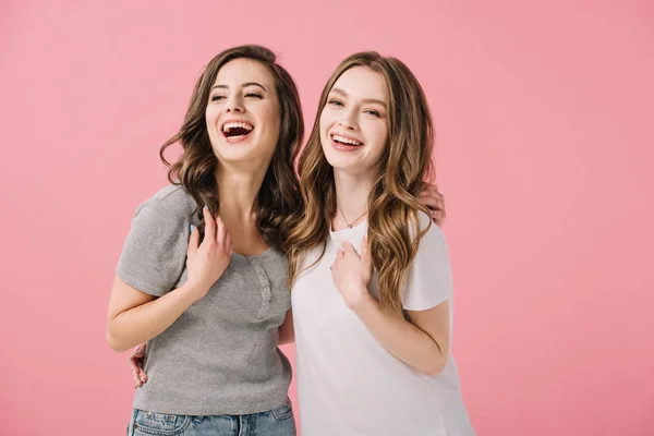 Mujeres atractivas y sonrientes en camisetas mirando a la cámara aislada en rosa - foto de stock
