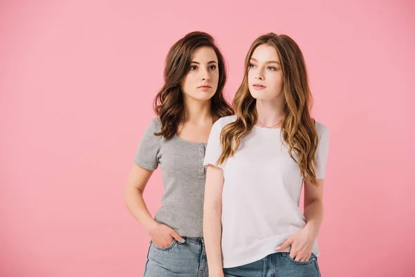 Привлекательные женщины в футболках, смотрящие в сторону, изолированные от розового — стоковое фото