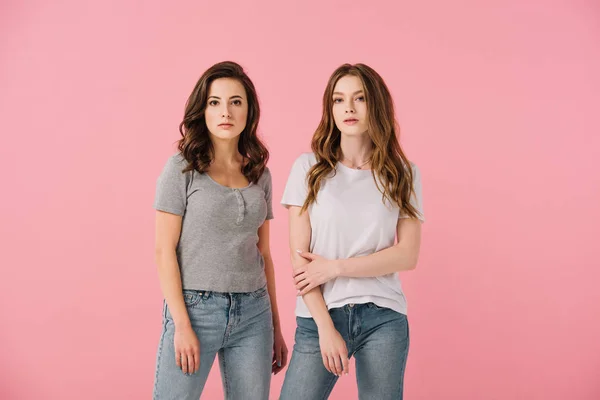 Attraktive Frauen in T-Shirts schauen vereinzelt in die Kamera auf rosa — Stockfoto