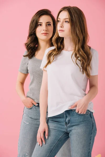 Mujeres atractivas en camisetas mirando hacia otro lado aisladas en rosa - foto de stock