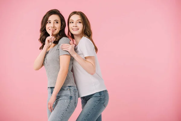 Mujeres atractivas en camisetas que muestran gesto shh aislado en rosa - foto de stock