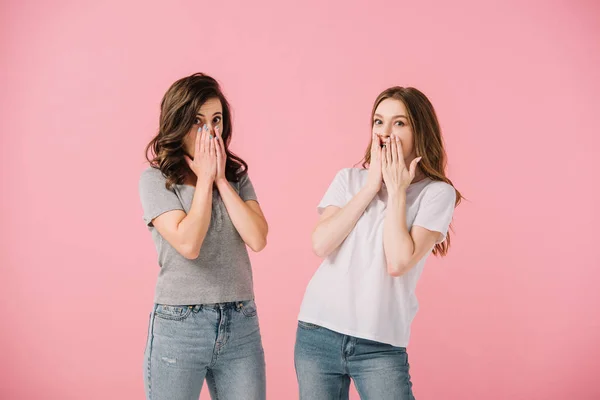 Attractive and shocked women in t-shirts looking at camera isolated on pink — Stock Photo