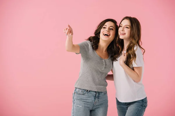 Donne attraenti e sorridenti in t-shirt che puntano con il dito isolato sul rosa — Foto stock