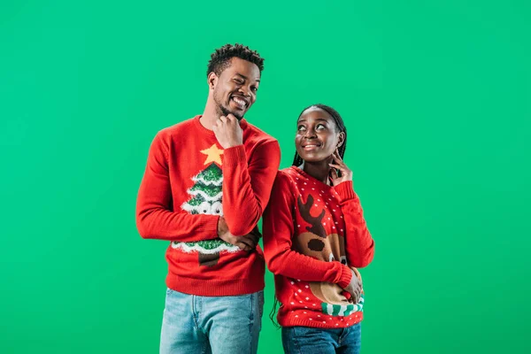 Pareja afroamericana en suéteres rojos de Navidad aislados en verde - foto de stock