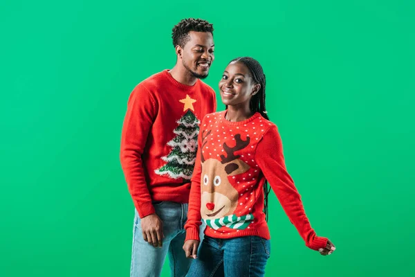 Pareja afroamericana en suéteres de Navidad aislados en verde - foto de stock