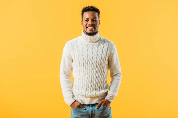 Africano homem americano em camisola de malha de mãos dadas em bolsos, sorrindo e olhando para a câmera isolada no amarelo — Fotografia de Stock