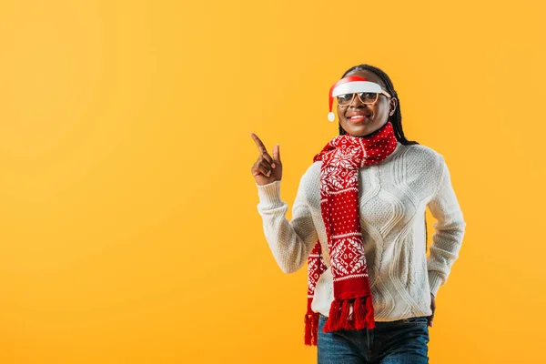 Mujer afroamericana en suéter de invierno y gafas de Navidad apuntando con el dedo aislado en amarillo - foto de stock