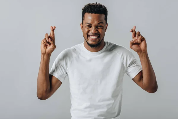 African American man holding fingers crossed and looking at camera isolated on grey — Stock Photo