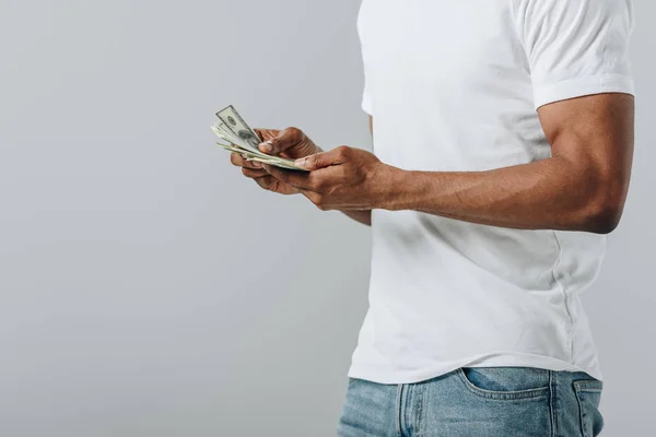 Vista recortada del hombre afroamericano contando billetes de dólar aislados en gris - foto de stock