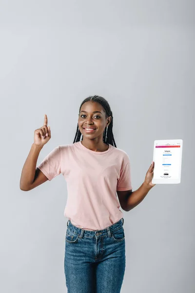 KYIV, UCRAINA - 2 AGOSTO 2019: Donna afroamericana con tablet digitale con app Instagram e segno di idea isolato su grigio — Foto stock