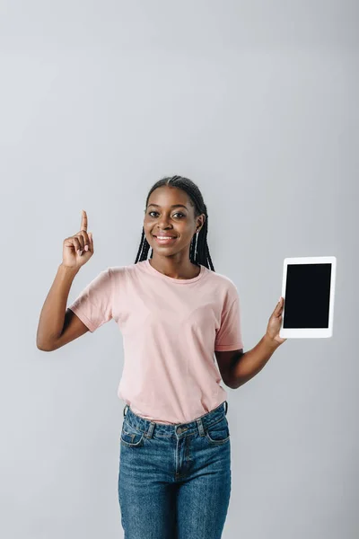 Femme afro-américaine tenant tablette numérique avec écran blanc et montrant le signe d'idée isolé sur gris — Photo de stock