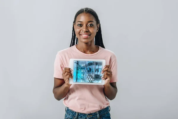 Donna afroamericana che mostra alla fotocamera tablet digitale con applicazione sanitaria isolata su grigio — Foto stock
