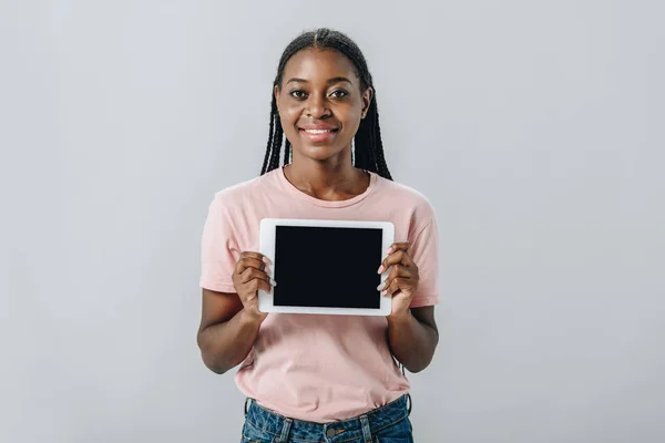 African American woman showing at camera digital tablet with blank screen isolated on grey — Stock Photo