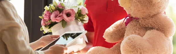 Panoramic shot of woman holding digital tablet near delivery man with presents — Stock Photo